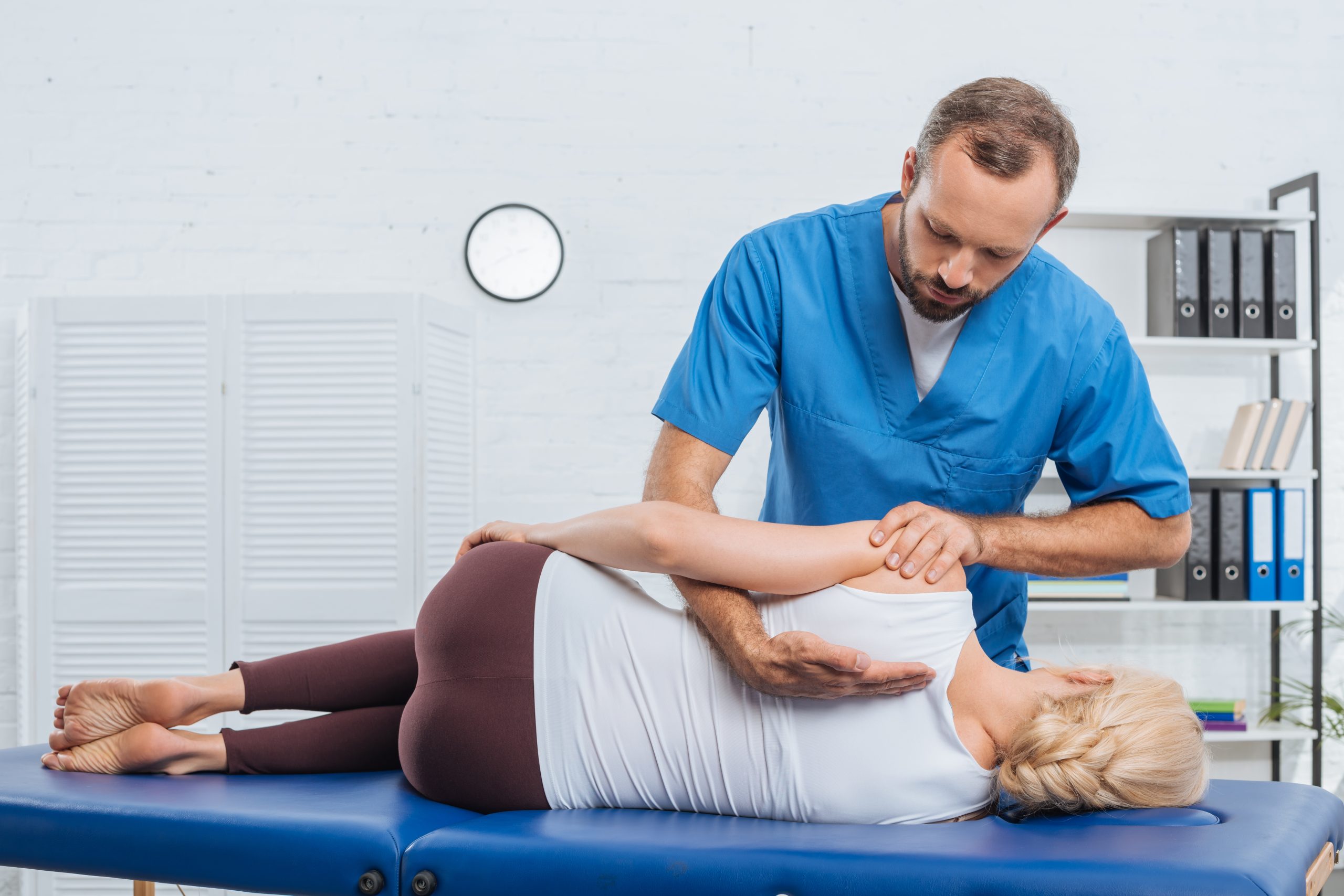 chiropractor massaging back of patient that lying on massage table in hospital